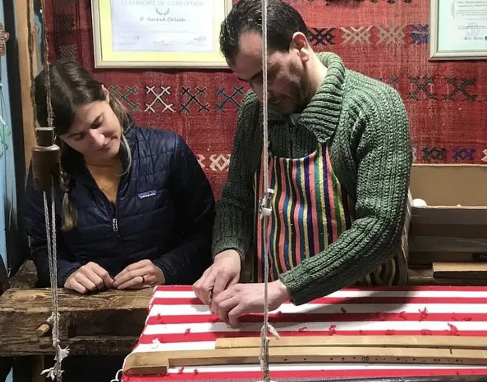 A workshop guest ties her first knots on the loom, guided by Rachid